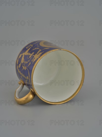 Cup, Manufacture nationale de porcelaine de Sèvres 1756-, manufacturer, 1803–1804, Sèvres; porcelain vessel, height 7.5 cm., A ceramic cup lying on its side with a white interior and a gold rim, a blue exterior decorated with gold ornamental patterns, and a gold-colored handle with a white inner curve, set against a neutral gray background.