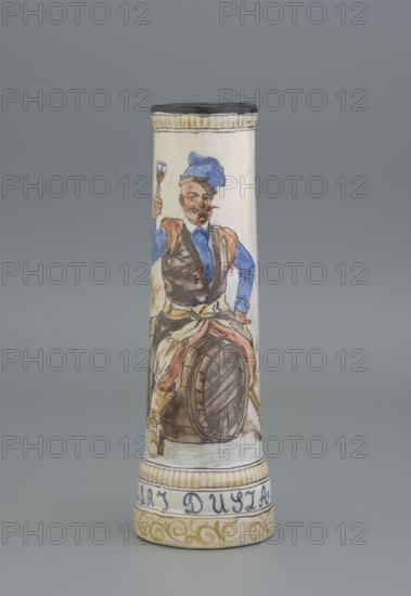 Mug. Maker: Hyzycka, Jadwiga 1856–1922, painter; Majolica Manufactory in Nieborów, manufacturer 1881–1899. Cylindrical mug, slightly tapering toward the top, with a handle. The mantle is decorated with an image of a nobleman sitting on a barrel holding a glass goblet in his right hand. A coat of arms next to the handle. Plant decoration. Inscription on the pedestal: Hulaj dusza. Date: 1881–1890. Place of origin: Nieborów Michal Piotr Radziwill's Majolica Manufactory. Tankard; height 28 cm, width 15 cm with handle; inlet diameter 6.5 cm; bottom diameter 9 cm., A tall cylindrical ceramic vessel decorated with a painted figure of a man wearing a blue hat and blue sleeves, a brown vest, and light-colored trousers, seated with one knee raised on a wooden barrel while holding a small glass; the painted scene includes brown, blue, beige, black, yellow, and hints of red tones; the rim of the vessel is dark with a band of yellowish stripes below it and a decorative band of yellow scrollwork nea...