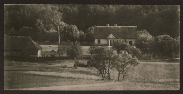 Backwater in Ponary, Ponary Lithuania, Vilnius environment, Bulhak, Jan 1876–1950 photographer, Ponary Lithuania, housing, residential architecture, ca. 1937, photograph, nature photograph, height 8.3 cm, width 17.0 cm, A sepia-toned rural scene shows a house with a pitched roof and a small porch set back amid trees and shrubs, with a few trees in the foreground on a grassy expanse; to the left a barnlike structure with a sloped roof stands closer to the foreground, and a tall slender pole rises near the center-left; behind the buildings a dense line of darker trees forms a backdrop, and the overall colors visible are shades of brown, beige, dark brown, and muted green.
