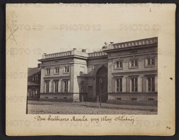 The Sculptor Manzel's House at Chlodna Street View of the front elevation of the house built for Jan Józef Manzel, photograph by Karol Beyer 1818–1877; related to Jan Józef Manzel 1806–1875 and Leopold Méyet 1850–1912. Subject: tenement house at Chlodna Street, Warsaw. Date: 1861–1863. Technique: photography, photographic print. Dimensions: print image 5.8 × 8.8 cm; support 11.3 × 8.8 cm., A sepia-toned photograph shows the façade of a classical building with a central archway flanked by symmetrical wings featuring rows of tall windows with shutters and decorative window surrounds; the roofline has a low parapet with ornamental elements and a sculptural group near the center, and a street lamp stands in front of the archway on a cobblestone street, with a smaller adjacent building visible at the left, and the overall colors visible are beige, brown, tan, black, and gray.