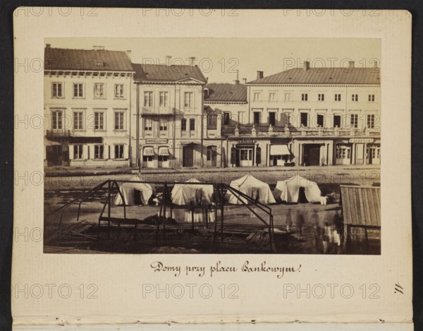Houses at Bankowy Square Eastern frontage of Rymarska Street with Aleksander Przezdziecki's palace and a fragment of the Meynders tenement house, photograph by Karol Beyer 1818–1877, 1861–1863. Depicts tenement houses, Meynders' tenement house Rymarska 6, Aleksander Przezdziecki 1814–1871 and related iconography, Frederick Albert Fryderyk Lessel 1767–1822 iconography, Boleslaw Podczaszynski 1822–1876 iconography, signs, mirrors, hairdressing, Russian army, military tents, martial law in the Kingdom of Poland 1861–1863. Photography; nature photography; photographic print: 6.2 × 9.6 cm; support: 11.3 × 8.8 cm., A sepia-toned photograph showing a row of multi-story buildings with light-colored facades and darker rooflines, a few with balconies and awnings, in front of which several white fabric tents are pitched on a flat waterfront area; in the foreground there is a dark wooden frame structure and a small shed with a slanted roof, and a few indistinct human figures near the water creatin...
