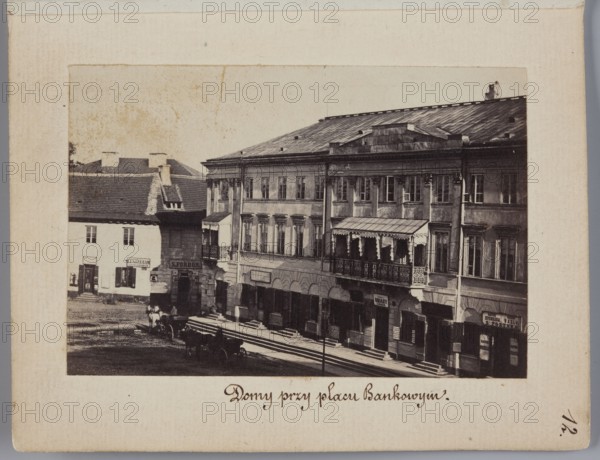 Houses at Bankowy Square View from the Polish Bank building on the Kossecka tenement house at Bankowy Square, corner of Zabia Street, Karol Beyer 1818–1877 photographer; tenement houses; Bankowy Square, Warsaw; Senatorska Street; Zabia Street; beer; signboards; currency exchange offices; Kossecka tenement house; 1861–1863; photography, nature photography; photographic print, height 6 cm, width 9 cm; backing height 11.3 cm, width 8.8 cm., A sepia-toned photograph shows a street scene with a row of connected multi-story buildings featuring many windows and a covered balcony with decorative railing, adjacent to a smaller building with a pitched roof and visible chimneys; a group of horse-drawn carts and a few people are on the cobbled street in front of the buildings, and the scene includes awnings, storefronts, and architectural details such as columns and cornices, with visible colors including shades of brown, beige, black, gray, and off-white.