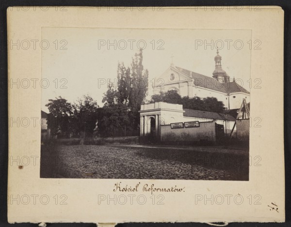 Reformati Church St. Anthony of Padua Church at Senatorska Street, Warsaw, photograph by Karol Beyer 1818–1877; view includes pavement and signs; created 1861–1863 in Warsaw; photographer Leopold Méyet 1850–1912 noted; photographic print nature photograph, image: 6.2 × 8.6 cm; backing: 11.3 × 8.8 cm., A vintage black-and-white photograph mounted on a cream-colored card shows a streetscape with a large classical building with a triangular pediment and a domed tower rising behind it, partially obscured by a group of tall trees and dense shrubbery. In front of the building is a low wall with an arched gateway and an adjoining single-story structure, and a cobblestone street runs across the foreground. The image palette includes shades of black, white, gray, cream, and sepia tones on the mounting.