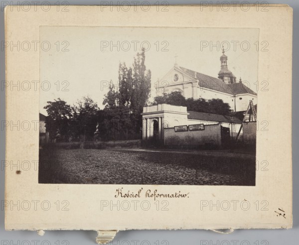 Warsaw. Reformati Church St. Anthony of Padua Church at Senatorska Street, Beyer, Karol 1818-1877 photographer, pavement, signs, Warsaw Masovian Voivodeship, St. Anthony of Padua Church Warsaw ; Sródmiescie, Reformati Church Warsaw, Senatorska Street Warsaw ; street, 1861 - 1863, Warsaw place of creation, photograph, nature photograph, photographic print: height 6.2 cm, width 8.6 cm, backing: height 11.3 cm, width 8.8 cm, A sepia-toned photograph mounted on a beige card shows a street scene with a group of trees and a building complex dominated by a church with a triangular pediment and a domed tower, visible behind a lower wall and gateway; the foreground is a cobblestone street leading toward the entrance, and there are a few signs mounted on the wall near the gateway; colors visible include shades of brown, beige, black, and off-white.
