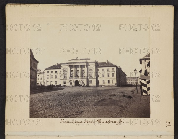 Warsaw. Commission of Internal Affairs Mostowski Palace rebuilt according to the design of architect Antonio Corazzi for the Government Commission of Internal Affairs and Police. On the left, the exit of Nowolipie Street onto Przejazd Street; on the right, in the background, buildings of Nowolipki Street, Beyer, Karol 1818-1877 photographer, cobblestones, street lamps, Mostowski Palace Warsaw, Warsaw Masovian Voivodeship, Przejazd Warsaw; street, Corazzi, Antonio 1792-1877, Government Commission of Internal Affairs and Police Warsaw; 1815-1831, Nowolipie Warsaw; street, Nowolipki Warsaw; street, 1861-1863, Warsaw, photography, photographic print: height 6.8 cm, width 8.2 cm, support: height 11.3 cm, width 8.8 cm, A sepia-toned photograph shows a broad cobblestone square with a large neoclassical building centered in the background, featuring a columned portico and decorative façades; the building is flanked by lower structures on either side. To the right foreground there is a sidewalk...