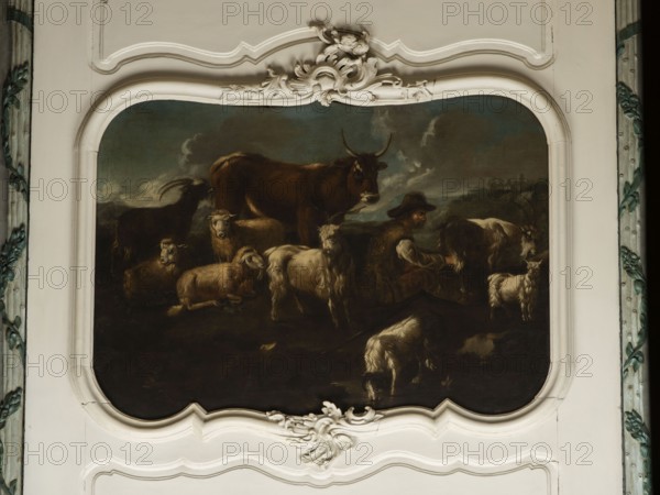 Shepherd's Scene with a Shepherd Milking a Goat, by Philipp Peter Roos 1657–1706. The overall tones are browns and dark blues. The surface is fully composed, the focal point is a cow standing at the back and a group of five animals—three sheep and two goats—filling the right side of the scene. On the right, a seated shepherd in a sheepskin coat and hat milks a cow into a wooden bucket. Next to a goat is a small white kid. At the front a dog laps water from a shallow pond. On the right background, city buildings are visible on a hill; the dark sky is covered with puffy clouds. In the upper corner is the Temple of the Sibyl in Tivoli. Several identical faces of sheep and rams appear. Attributed to Philipp Peter Roos Rosa di Tivoli, born August 30, 1657 in Sankt Goar, died January 17, 1706 in Rome. 18th century, Italy. Overdoor; height 91.0 cm, width 127.0 cm., A painted scene set within an ornate white frame shows a group of farm animals and a seated man; visible animals include several ...