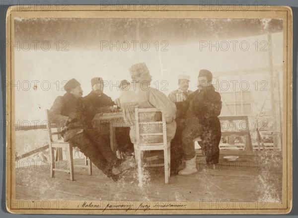 Six painters seated at a table on the central platform in the rotunda painting the Raclawice Panorama; from the left: Tadeusz Popiel, Jan Styka, Wlodzimierz Tetmajer, Michal Sozanski back, Wojciech Kossak, Ludwig Boller, Hamel and Feigl photographic studio, ca. 1893–1894. Photography, print glued to cardboard, photographic print: 11.7 × 17.3 cm; cardboard: 13.5 × 18.5 cm. Subjects and artists: Panorama of the Battle of Raclawice; painters’ studio, scaffolding, portraits of artists. Identified persons: Kossak, Wojciech 1856–1942; Styka, Jan 1858–1925; Popiel, Tadeusz 1863–1913; Sozanski, Michal 1853–1923; Boller, Ludwig 1862–1896; Tetmajer, Wlodzimierz 1861–1923., A sepia-toned photograph showing a group of men seated around a small table under a covered wooden structure, the scene dominated by brown, beige, cream, and muted gray tones; the men wear a mix of dark and light outer garments and hats in shades of black, brown, and gray, and one man facing away wears a lighter-colored coat w...