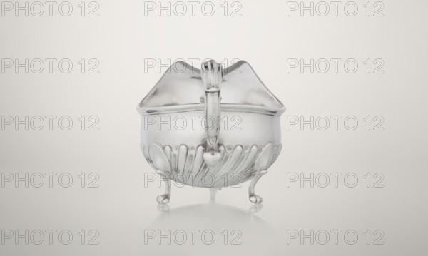 Gravy boat, Charles Stuart Harris fl. 1852–1897, maker; Harris, C.S. & Sons London; goldsmith's firm, fl. 1817–1933, firm. Oval gravy boat supported on three volute legs with an S-shaped handle; wide rim on the axis. Bottom decorated with alternating convex and concave clasps. Side engraved with the Leszczyc Radolinski family coat of arms; bottom inscribed II RAD MAJ I 748, 1892/1893. England, London. Vessel; height 10 cm, width 22.5 cm, weight 167.5 g., A metallic, reflective bowl-like object with a lid and a central handle sits on a smooth surface; it rests on a group of ornate curved legs and shows embossed, scallop-like decorative ridges around its lower half, with a rounded top formed into a peaked lid. The visible colors are silver tones on the object and a pale off-white to light gray background with soft gradients, and faint reflections of those colors on the surface beneath.
