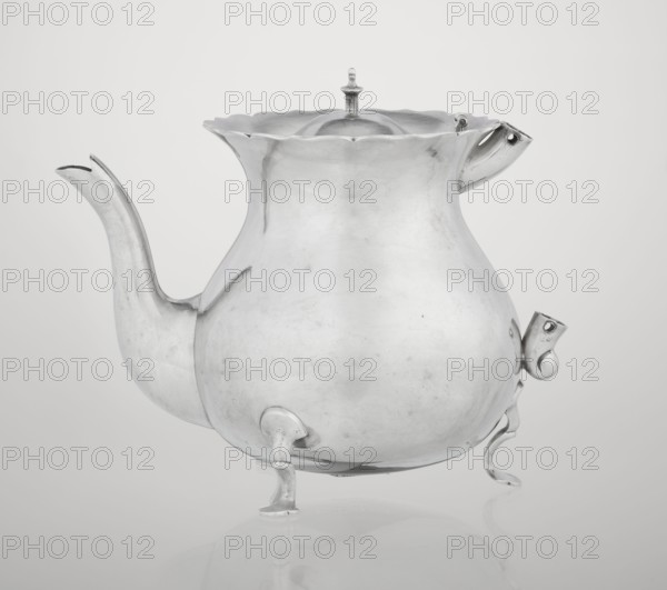 Teapot by Stokes & Ireland Ltd Birmingham; goldsmiths; active 1872–1925. Pear-shaped teapot supported on three legs, smooth, with a flared upper edge topped with a pinnacle, with a spout-shaped spout; on the axis are silver bushings for mounting the missing wooden handle. Dated 1900–1901. Origin: Chester, England, Great Britain. Vessel; height 11.5 cm, width 15.5 cm, depth 10 cm, weight 330 g., A metallic teapot with a rounded, bulbous body sits on a reflective surface, supported by a group of curved legs; it has a long, elegantly curved spout on one side and a shorter angled spout-like fixture on the opposite side, and a scalloped rim with a domed lid topped by a small finial. The visible colors are shades of silver and gray, with subtle highlights and shadows creating lighter and darker silvery-gray tones across the surface.
