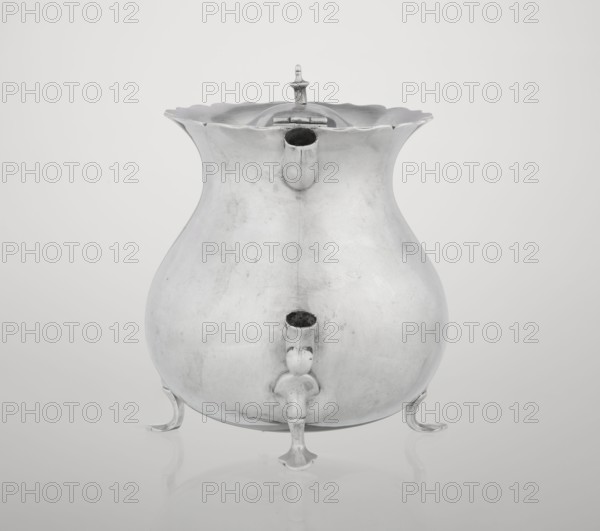 Pear-shaped teapot supported on three legs, smooth, with a flared upper edge topped with a pinnacle, with a spout-shaped spout, on the axis silver bushings for mounting the missing wooden handle. Maker: Stokes & Ireland Ltd Birmingham; goldsmiths; fl. 1872–1925. Date: 1900–1901. Place: Chester, England, Great Britain. Material/function: vessel teapot. Dimensions: height 11.5 cm; width 15.5 cm; depth 10 cm; weight 330 g., A reflective metal vessel with a bulbous body and a flared, scalloped rim sits on a smooth surface, supported by a group of curved legs. The vessel has a short spout near the top and a larger spout-like protrusion lower on its front, each appearing hollow. A hinged lid with a small finial rests at the top center. The image shows shades of silver, gray, and white with soft shadows and faint surface marks on the metal.