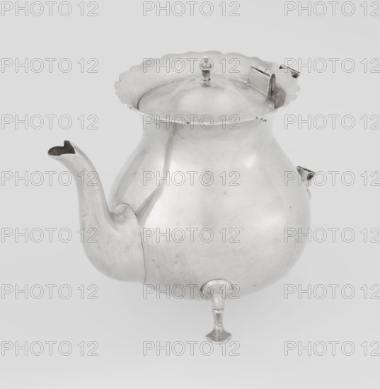 Teapot by Stokes & Ireland Ltd Birmingham; goldsmiths; fl. 1872–1925. Pear-shaped teapot supported on three legs, smooth, with a flared upper edge topped with a pinnacle, with a spout-shaped spout; on the axis are silver bushings for mounting the missing wooden handle. Inscribed/corporate slogans of maker. Made 1900–1901, Chester, England, Great Britain. Vessel. Height 11.5 cm; width 15.5 cm; depth 10 cm; weight 330 g., A rounded metal vessel with a bulbous body and a flared scalloped rim, shown from a slightly elevated angle; it has a curved spout on one side and a hinged lid with a small finial on top, and it stands on a small turned foot. The visible colors are silver and shades of gray on a light gray background.