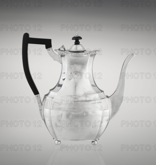 Coffee pot by Harris, CS & Sons London; goldsmiths' firm; fl. 1817–1933 and Harris, Charles Stuart fl. 1852–1897. Scrap-purchased; ribbed, pear-shaped coffee vessel supported on four ball-shaped profiled legs. Belly decorated with a band of narrow half-cylinders and grooves; high spout-like handle to the side and a wooden axial handle contemporarily added set in silver sockets. Upper edge edged with a godron band; hinged lid domed in the center topped with a bowling-pin finial. 1895/1896. London, England. Height 21.2 cm; width 18.5 cm; depth 10 cm; weight 640 g., A reflective metal teapot with a curved spout and a tall, angular body standing on small round feet, featuring a dark handle and a domed lid topped with a small dark finial; the teapot has horizontal ribbed decoration around its midsection and a subtle scalloped rim on the lid, with visible surface scratches and reflections; the background is a smooth gradient from light gray at the center to darker gray toward the edges.