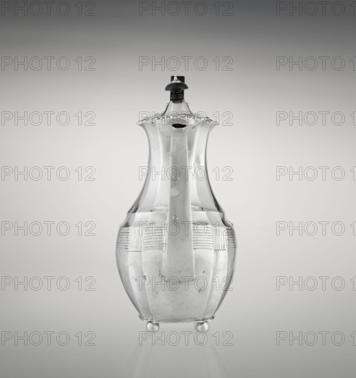 Coffee pot by Harris, CS & Sons London; goldsmiths' firm, fl. 1817–1933 and Charles Stuart Harris fl. 1852–1897. Scrap-purchased. Pear-shaped, ribbed coffee vessel with godron ornaments; supported on four profiled, ball-shaped legs. Belly decorated with a band of narrow half-cylinders and grooves. High side spout-like handle and a wooden handle added later, mounted on the axis in silver sockets. Upper edge finished with a godron band. Hinged lid, domed in the center, topped with a bowling-pin finial. Dated 1895/1896. Great Britain London, England. Height 21.2 cm; width 18.5 cm; depth 10 cm; weight 640 g., A transparent glass vessel with a curving, elongated body and a narrow neck topped by a lid with a dark small knob, resting on a few small spherical feet; the vessel shows decorative horizontal ridged bands around its midsection and a smooth handle-like projection down its front, all shown against a gradient background with shades of gray and white.