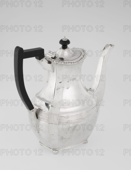 Coffee pot by Harris, CS & Sons London; goldsmiths' firm, fl. 1817–1933 and Charles Stuart Harris maker, fl. 1852–1897. Scrap-purchased. Pear-shaped, ribbed coffee vessel with godron ornaments; belly decorated with a band of narrow half-cylinders and grooves. Supported on four profiled, ball-shaped legs. High handle in the form of a spout on the side; wooden handle contemporary addition on the axis set in silver sockets. Upper edge edged with godron band; hinged lid, domed in the center, topped with a bowling-pin finial. Dated 1895/1896. Great Britain, London, England. Height 21.2 cm; width 18.5 cm; depth 10 cm; weight 640 g., A silver metal teapot with a reflective surface and a rounded body sits against a pale gray background; it has a curved spout and a hinged lid topped with a small black finial, a decorative rim around the lid, and a black angular handle attached to the body; the body shows ribbed horizontal bands and a rectangular ribbed panel, with small round feet at the base a...