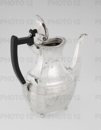Coffee pot by Harris, CS & Sons London; goldsmiths' firm, fl. 1817–1933 and Charles Stuart Harris maker, fl. 1852–1897. Purchased; scrap — purchased. Pear-shaped, ribbed coffee vessel with godron ornaments; belly decorated with a band of narrow half-cylinders and grooves. Supported on four ball-shaped, profiled, ribbed legs. High side spout-shaped handle and a contemporarily added wooden axial handle set in silver sockets. Upper edge edged with godron band; hinged lid domed in the center, topped with a bowling-pin finial. Dated 1895/1896. Great Britain, London, England. Height 21.2 cm; width 18.5 cm; depth 10 cm; weight 640 g., A metal pitcher with a hinged lid and tall curved spout sits against a pale background, the pitcher showing a reflective silver surface with visible scratches and small dents; it has a rounded body that tapers to a narrower neck with a decorative ridged rim and a band of horizontal grooves around the midsection interrupted by a textured rectangular panel, and it...