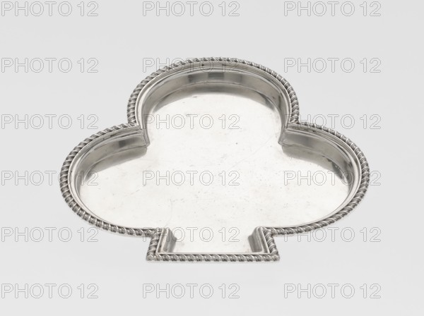 Tray, Hukin & Heath Birmingham; London; goldsmiths' firm; fl. 1855–1953 maker, Heath, John Thomas & Middleton, John Hartshorne makers, club-shaped tray with a smooth mirror surrounded by a raised half-cylinder with an edge decorated with an ornament of diagonal godrons; scrap; godron ornaments; 1897/1898; Great Britain, England, London; table accessory; height 1.1 cm, width 12.5 cm, depth 11.9 cm, weight 86 g, A silver metal tray in the shape of a clover with scalloped lobes and a flat tab-like extension, featuring a raised twisted rope border and a smooth reflective interior surface showing light scratches; colors visible are silver and shades of gray against a pale gray background.