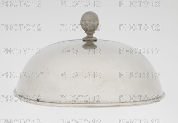 Platter lampshade, Scott, Digby & Smith, Benjamin fl. 1802–1807 goldsmith; silver hemispherical lampshade with a non-original handle, smooth, ribbon edge, profiled; relief plaque with the Czartoryski coat of arms on a paludament, under a princely mitre, with labres and the motto Be that as it may.; handle is contemporary. 1803/1804; London, England, Great Britain. Vessel; height 8.5 cm, diameter 15.2 cm, weight approx. 230 g., A shiny metal dome-shaped object with a rounded knob on top, shown against a pale background; the dome is metallic silver with some darker scuff marks and light scratches, and the knob is a weathered gray with a faint reflection on the dome surface.