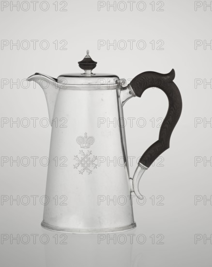 Conical coffee pot with hinged lid, slightly arched and flattened at the top, topped with a wooden handle; short spout; on the axis two sleeves for attaching a wooden handle added contemporarily. On the mantle engraved monogram tied HH beneath a ducal mitre; monograms, rank crowns, ducal mitre heraldry. Maker: Edward Barnard & Sons Ltd., London goldsmiths, fl. ca. 1680– . Also associated makers/sellers: Clark, Alfred Ltd., London goldsmiths and sellers, fl. 1898–1934. Materials: silver; wooden handle made. Function: coffee ware. Date inscription: 1890/1891. Place: London, England, Great Britain. Dimensions: height 17.3 cm, width 11 cm, depth 8.4 cm; weight 627 g., A tall metallic pitcher with a reflective silver surface and a dark wooden curved handle is shown against a plain light gray background; the pitcher has a hinged lid topped by a small dark finial, a short spout, subtle decorative ridges near the base and rim, and a faint engraved emblem on its front; visible colors include si...