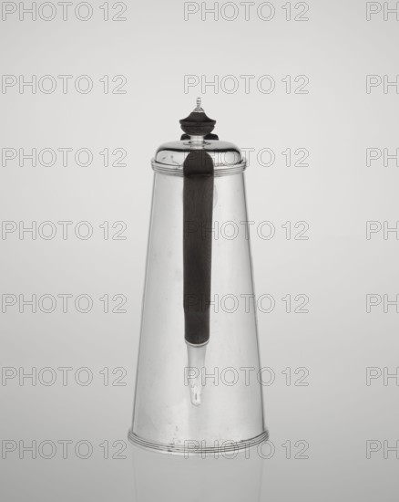 Conical coffee pot with hinged lid, slightly arched and flattened at the top, topped with a wooden handle made; short spout on axis with two sleeves for attaching a wooden handle added contemporarily. Engraved monogram tied HH beneath a ducal mitre; inscribed/dated 1890/1891. Maker: Barnard, Edward & Sons Ltd London; goldsmiths; active ca. 1680– ; also associated with Clark, Alfred Ltd London; goldsmiths and sellers; active 1898–1934. Materials: silver with wooden handle. Function: coffee ware. Place: London, England, Great Britain. Dimensions: height 17.3 cm, width 11 cm, depth 8.4 cm; weight 627 g., A tall conical metal container with a reflective silver surface and a dark vertical handle running down its front; the container has a rounded lid topped with a small decorative finial that combines silver and dark material, and a narrow spout extending from the handle area; the background is a smooth light gray gradient and the visible colors are silver, dark brown or black, and shades o...
