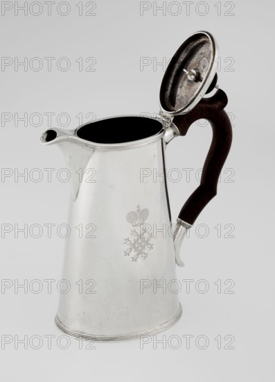 Conical coffee pot with hinged lid, slightly arched and flattened at the top, topped with a wooden handle made; short spout; on the axis two sleeves for attaching a wooden handle added contemporarily. Maker: Barnard, Edward & Sons Ltd London; goldsmith's firm; fl. ca. 1680– . Also associated with Clark, Alfred Ltd London; goldsmith's firm and sellers; fl. 1898–1934. Engraved monogram tied HH beneath a ducal mitre; date inscribed 1890/1891. Materials: silver with wooden handle. Function: coffee ware. Place: London, England, Great Britain. Dimensions: height 17.3 cm; width 11 cm; depth 8.4 cm; weight 627 g., A silver pitcher with a hinged lid is shown against a light gray background, the lid open to reveal a dark interior and the underside of the lid; the pitcher has a tapered body with a spout and a dark wooden handle with a curved shape and a silver mounting, and the surface shows a faint decorative emblem; visible colors include silver, dark brown, black, and light gray.