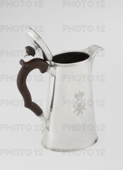 Conical coffee pot with hinged lid, slightly arched and flattened at the top, topped with a wooden handle made; short spout on the axis and two sleeves for attaching a wooden handle added contemporarily. Engraved monogram tied HH beneath a ducal mitre, dated 1890/1891. Maker: Edward Barnard & Sons Ltd London, goldsmiths, fl. ca. 1680– . Also associated with Clark, Alfred Ltd London, goldsmiths and sellers, fl. 1898–1934. Materials: silver with wooden handle. Function: coffee ware. Dimensions: height 17.3 cm, width 11 cm, depth 8.4 cm; weight 627 g., A metal pitcher with a hinged lid and a curved wooden handle sits against a plain light gray background; the pitcher is shiny silver in color with a slightly tapered cylindrical body, a spout at the top, and a dark interior visible under the open lid, while the handle is dark brown with visible wood grain and an ornate curved shape, and the lid has a small dark brown knob matching the handle.