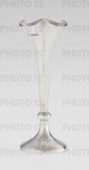 Chalice-shaped vase by Woodward, Horace & Co Ltd Birmingham, London; active ca. 1851–1919. Manufacturer's marks and corporate slogans present. Scraps of purchase, Vessel decorated with flowers and pearling ornament; vase supported on a circular foot, transitioning into a short stem terminating in a ring, with a goblet in the form of a slender flower calyx; tall, conical, quarter-part at the top, edged with pearling. Dated 1899/1900. Made in England, Great Britain, London. Vessel; height 12.5 cm, width 5.5 cm, depth 5.5 cm; weight 38 g., A tall, slender metal vase with a flared, scalloped rim sits against a light gray background; the vase has a smooth, reflective silver surface showing subtle scratches and small spots of tarnish, a long tapered stem with a rounded knop near the base, and a gently domed circular foot with a reflective sheen.