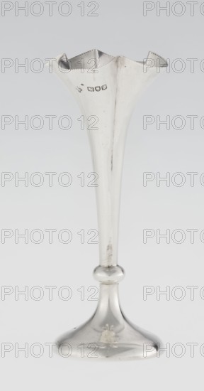 Chalice-shaped vase, maker: Woodward, Horace & Co Ltd Birmingham, London; fl. ca 1851–1919; corporate slogans / goldsmith's firm; purchase provenance; scrap - purchase. Flowers vessel, pearling ornament. Vase supported on a circular foot transitioning into a short stem terminating in a ring, with a goblet in the form of a slender flower calyx; tall, conical, quarter-part at the top edged with pearling. Date: 1899/1900. Place: Great Britain — England, London. Vessel. Height 12.5 cm; width 5.5 cm; depth 5.5 cm; weight 38 g., A tall slender metal vessel with a flared, scalloped rim and a narrow elongated stem widening into a rounded knop and a domed base; the surface is reflective and shows areas of slight tarnish and small scratches; visible colors include silver tones on the metal and subtle gray variations in the background.