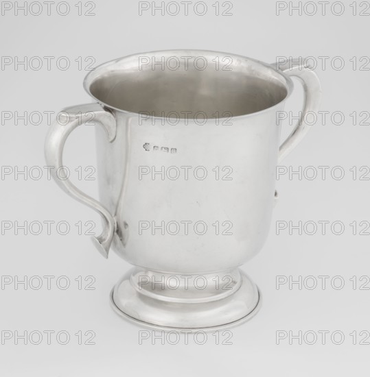 Two-eared vase, vase on a circular, stepped-profile foot and short stem, smooth, cylindrical, with a slightly upturned upper edge, two profiled, volute-shaped handles on the sides, 1926/1927, Great Britain, Birmingham, England, vessel, height 15 cm, width 21 cm, depth 13.5 cm, weight 540 g, A silver-colored metal cup with a rounded rim and a flared base, shown against a light gray background; the cup has two handles on opposite sides with curved shapes, a smooth reflective surface with a few small scuffs and darker spots, and the interior appears slightly darker silver than the exterior.