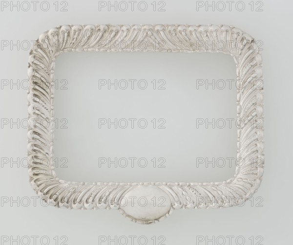 Dressing mirror frame by Comyns & Sons London; goldsmiths; fl. 1859–1953. Rectangular mirror frame with rounded corners decorated with an oblique clasp and oval medallion; includes clasp and medallion ornament. Date: 1890–1891. Materials/role: goldsmiths' firm. Place: London, England, Great Britain. Function: dressing accessory/frame. Dimensions: height 15.7 cm; width 13.2 cm; depth 2 cm; weight 102 g., A decorative rectangular frame with rounded corners shown against a pale gray background; the frame has an ornate raised pattern of curved featherlike motifs and small rounded beads all over its surface, and a smooth oval cartouche centered on the bottom edge. The visible colors are silver, light gray, off-white, and subtle darker gray shading in the recessed areas.