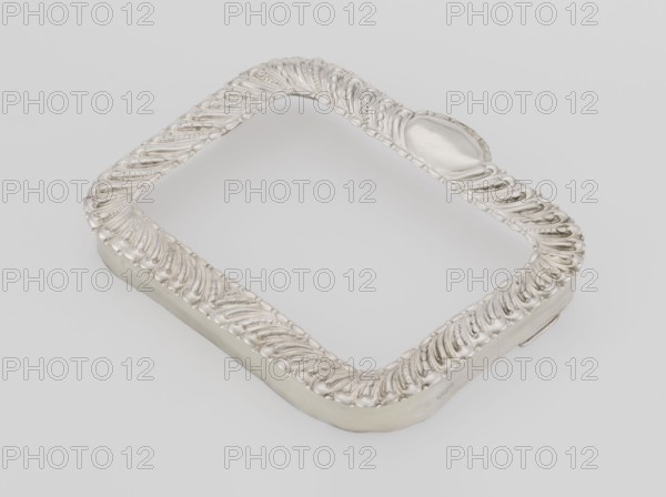 Dressing mirror frame; maker: Comyns & Sons London; goldsmiths; fl. 1859–1953; corporate slogans; goldsmiths' firm; scrap - purchase; purchase provenance; clasp; medallion ornament; rectangular mirror frame with rounded corners decorated with oblique clasp and oval medallion; 1890/1891; Great Britain, England, London; dressing accessories, frame; height 15.7 cm, width 13.2 cm, depth 2 cm, weight 102 g, A silver ornamental rectangular frame with rounded corners rests on a light gray background, the frame showing an ornate raised repeating leaf-like pattern along its top surface and a smooth inner and outer edge, with the metal reflecting highlights and shadowed contours in shades of silver and gray.