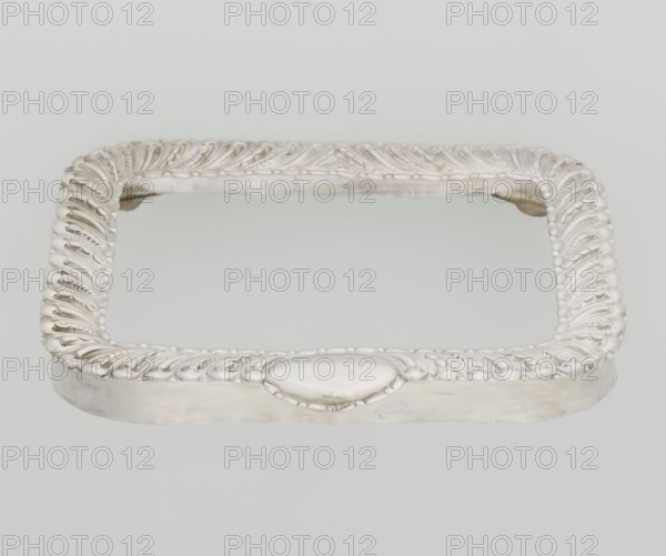 Dressing mirror frame by Comyns & Sons London; goldsmiths; active 1859–1953. Rectangular mirror frame with rounded corners decorated with an oblique clasp and oval medallion; includes clasp and medallion ornament. Scrap - purchase; purchase provenance. 1890–1891. Great Britain; England; London. Dressing accessory/frame. Height 15.7 cm; width 13.2 cm; depth 2 cm; weight 102 g., A rectangular ornate frame with rounded corners resting on a light background, finished in a silvery color with polished and slightly matte areas; the frame edge is decorated with a repeating raised swirl and bead pattern in the same silver tone, and there is a smooth oval cartouche on one side; inside the frame the surface appears reflective with pale gray and off-white tones; overall colors visible are silver, pale gray, off-white, and a hint of beige.