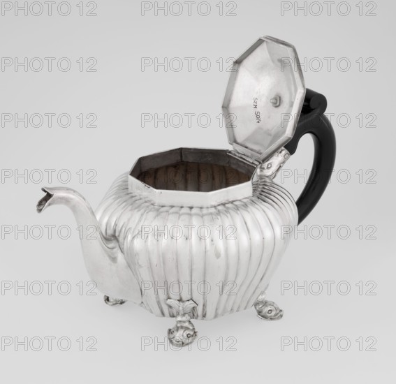 Teapot, maker: Thomas II fl. 1798–1809?, goldsmith. Teapot supported on four legs in the form of dolphins; octagonal body decorated with vertical narrow ringlets and flutes; spout-shaped spout; slightly arched hinged lid with wooden handle not original; additional wooden handle not original mounted in sockets. Iconography: dolphin. Function: tea vessel. Date: 1808/1809. Place: London, England, Great Britain. Dimensions: height 12 cm, width 20.5 cm, depth 14 cm; weight 595 g. Materials: silver scrap; classification: vessel., A rounded, ribbed metal teapot with an open octagonal lid and a curved spout sits on a plain background; the teapot is primarily silver with a glossy black handle, the interior of the teapot appearing darker and slightly tarnished, and the teapot rests on several decorative feet that match the silver body.