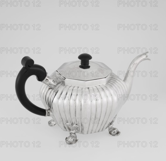 Teapot, Holland, Thomas II fl. 1798–1809? goldsmith; scrap - purchase; tea vessel; dolphin iconography; ringing; tea vessels. Teapot supported on four legs in the form of dolphins; octagonal; decorated with vertical narrow ringlets and flutes; spout-shaped spout; wooden handle not original mounted in sockets; slightly arched hinged lid; wooden handle not original. Date: 1808/1809. Place: Great Britain, England, London. Vessel. Height 12 cm; width 20.5 cm; depth 14 cm; weight 595 g., A silver teapot with a ribbed, rounded body stands on a group of decorative feet and has an elongated curved spout and an octagonal lid topped with a black round knob; the handle is black and curved, attached to the body with silver fittings. The visible colors are silver and black, set against a pale gray background.