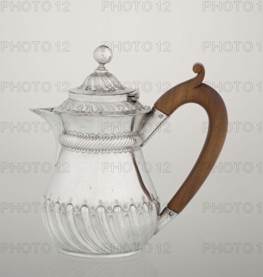 Coffee pot by John Septimus Beresford London; goldsmith's firm; active 1880–1889. Pear-shaped jug, spirally clacked in the lower part, smooth above, decorated with a half-cylinder under the upper flared rim; short spout-shaped spout; wooden handle not original mounted in sleeves; hinged, domed lid, spirally knotted, topped with a ball. 1888/1889. Great Britain — England, London. Vessel. Height 13 cm; width 12 cm; depth 6.8 cm; weight 179 g., A silver pitcher with decorative ridged and scalloped patterns and a rounded lid topped by a spherical finial, featuring a curved wooden handle in brown attached with metal fittings; the pitcher shows reflective silver surfaces and engraved ornamentation, set against a pale neutral background with visible highlights and soft shadows.