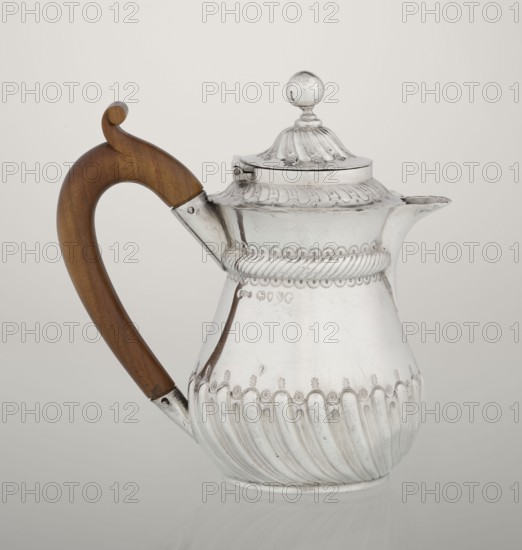 Coffee pot by John Septimus Beresford London goldsmith, active 1880–89. Pear-shaped jug, spirally flacked in the lower part, smooth above, decorated with a half-cylinder under the upper flared rim; short spout; wooden handle not original mounted in sleeves; hinged domed lid, spirally knotted, topped with a ball. Dated 1888–1889. Great Britain, England, London. Vessel. Height 13 cm, width 12 cm, depth 6.8 cm, weight 179 g., A silver pitcher with ornate embossed patterns and a rounded fluted lower body sits against a pale background, featuring a domed lid topped with a round finial and a scalloped decorative rim; a curved wooden handle in warm brown attaches to the body with metal fittings, and a short spout extends from the opposite side. Colors visible include silver, warm brown, and pale gray.