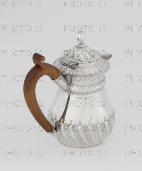 Coffee pot by John Septimus Beresford London goldsmith, active 1880–89, 1888–1889. Pear-shaped coffee pot, spirally chased in the lower part and smooth above, decorated with a half-cylinder under the flared rim; short spout; wooden handle not original mounted in sleeves; hinged domed lid, spirally knotted and topped with a ball. Material: silver. Dimensions: height 13 cm, width 12 cm, depth 6.8 cm; weight 179 g. Great Britain — England, London., A silver pitcher with ornate raised ribbed and floral detailing and a hinged domed lid topped by a round finial sits against a plain light gray background, the pitcher featuring a curved wooden handle in warm brown attached near the rim and base, and a short spout projecting from the opposite side; the metal shows polished reflective silver tones with subtle darker tarnish accents, and the wood shows smooth brown grain.