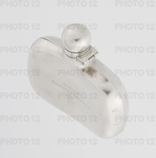 Hip flask by James Dixon & Sons Sheffield; goldsmiths; active from 1806. Silver hip flask, smooth, cuboid with rounded edges, narrow neck with spherical hinged stopper. Engraved JAN / TRUE FRIENDS. 1925/1926. Sheffield, England. Vessel. Height 9.9 cm; width 9.6 cm; depth 2.6 cm; weight 110 g., A smooth, reflective metal object with a rounded, flattened body and a spherical cap attached by a small hinged piece, shown against a pale gray background; the metal surface shows bright silver tones with areas of darker gray reflections and subtle scratches, and there are a few small dents and smudges visible on the curved surfaces.