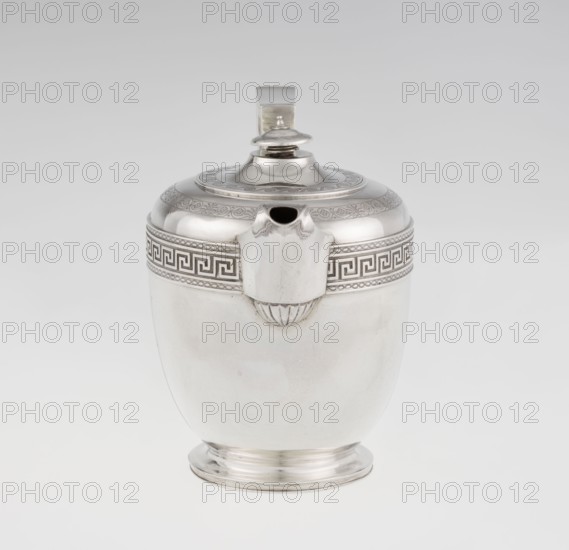Teapot by John Emes fl. 1796–1808, goldsmith. Ovoid teapot on a circular base with lid; height 17.9 cm, width 23.7 cm, weight 815 g. Decorated on the upper belly with a wide band of meander ornament and braid; ribbon-shaped, broken handle decorated with braid. Spout set high, decorated at the base with a stylized palmette. Lid finished with a knop. Engraved coat of arms on one side of the belly, cross on the other. Styles: Empire, George III/Georgian. Inscribed/dated 1806/1807, London, England. Materials: silver tea vessel., A single metallic vessel with a rounded body, short flared base, and a domed lid topped by a small finial, shown against a light gray background. The vessel is primarily silver in color with polished reflective surfaces, and it has a decorative band near the top featuring a geometric repeating pattern in darker silver tones. A spout-like projection at the front interrupts the band, and a vertical handle rises from the back of the lid in the same silver finish. The ...
