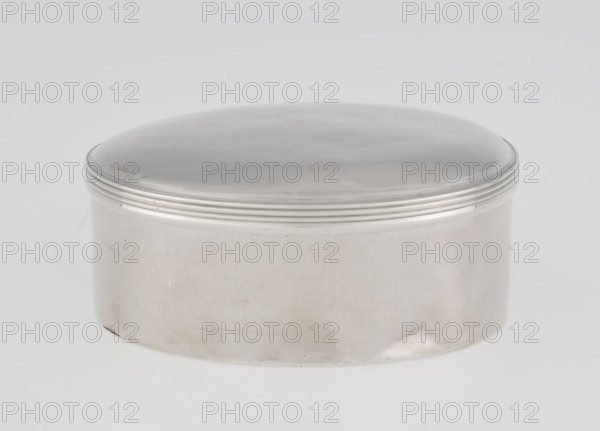 Toilet box by Edward Fernell fl. 1779–1796?, goldsmith. Round box, smooth with a slightly domed lid edged with a profiled band. Georgian/Classicism/George III style. Date: 1792–1793. Material/technique: presumably gold/silver scrap? Function: container for toilet accessories. Place of origin: London, England, Great Britain. Dimensions: height 4.2 cm, diameter 8.2 cm, weight 115 g., A smooth, round metal container with a domed lid sits on a flat surface; the container and lid are silvery and reflective with a few subtle darker and lighter patches, and the lid edge has a group of thin concentric ridges. The background is a light gray to off-white, and the surface beneath the container is a slightly lighter shade.