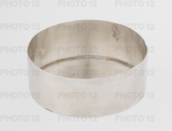 Toilet box; maker: Edward Fernell fl. 1779–1796?, goldsmith; material: scrap, function: toilet accessories/container; form: round box, smooth with slightly domed lid edged with a profiled band; style: Georgian, Classicism, George III; date: 1792/1793; origin: London, England, Great Britain; dimensions: height 4.2 cm, diameter 8.2 cm; weight 115 g., A round, shallow metal container with smooth curved sides and an open top sits on a plain light background; the metal surface shows a muted silvery-gray color with subtle variations in tone, faint scratches, and a few small darker spots, and the interior rim displays a slightly darker band and some areas of discoloration.