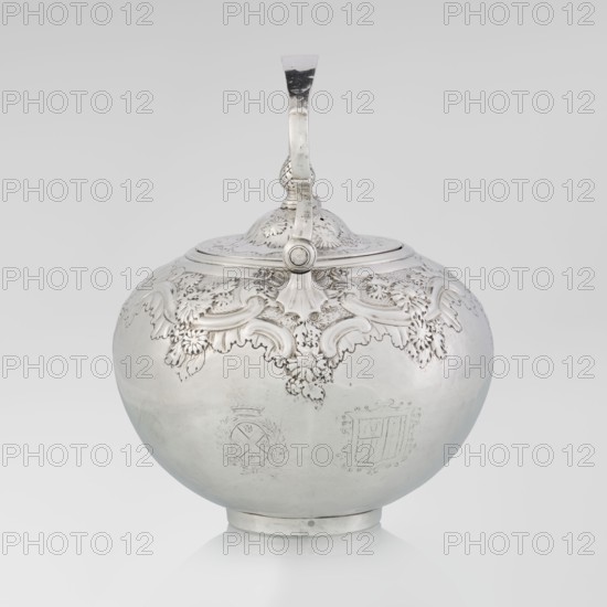 Buliera kettle for boiling water by Benjamin Gignac fl. 1745–1774, goldsmith. Rococo/rocaille style with Georgian/George II influences. Spherical buliera with a flat bow mounted on volutes; spout-shaped side spout; centrally arched cover topped with a pine cone. Decorated with repoussé rococo ornament and floral/plant motifs. Two engraved coats of arms among the decoration — a four-field one in an oval beneath a baronial crown and a second illegible shield. Missing base with a heater. Dated 1753/1754, London, England, Great Britain. Vessel; height 22 cm, width 24 cm, depth 19 cm; weight 848 g., A rounded metal vessel with a hinged domed lid and a curved handle extending from the top is shown against a plain light background. The vessel has ornate raised decorative motifs around the upper portion, including flowing leaf and scroll shapes with textured detailing. The lower surface of the vessel is smooth and reflective with subtle variations in sheen. The handle and lid have matching dec...