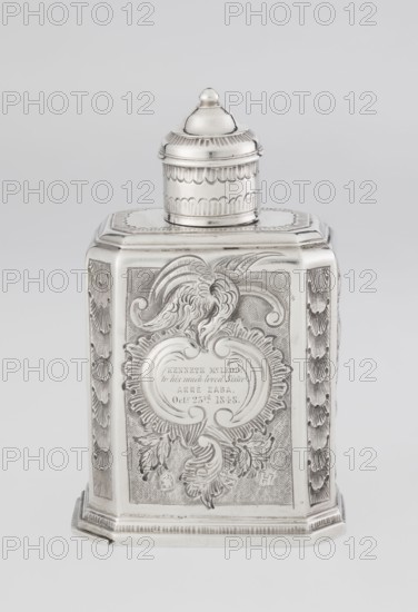 Tea caddy, Nash, Bowles fl. 1720–ca.1725 goldsmith; rococo; tea accessory; rocaille and floral roses, flowers ornament. Cuboid tea caddy with circular domed lid and a bowl on top; chamfered side edges; movable slide-in bottom. Surface decorated with repoussé floral and rocaille motifs on a grained background; front with an oval rocaille cartouche topped by an eagle, engraved inscription inside: KENNETH Mc LEOD, / to his much loved Sister / ANNE ZABA, / Octr 23 rd 1848; back wall with a bouquet of flowers; side walls with blooming, leafy roses. Engraved A on the bottom. Dated 1723/1724 tins; mid-19th century decoration. Place of origin: London, England. Vessel. Height 12 cm; width 7.7 cm; depth 5.7 cm; weight ca. 230 g., A silver-colored metal container with a rectangular base and a domed, removable lid sits against a light gray background. The main body has ornate engraved and embossed decoration including flowing acanthus-like foliage, curved cartouche shapes, and textured panels on t...