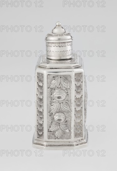Tea caddy by Nash, Bowles fl. 1720–ca. 1725, goldsmith; rococo style. Cuboid tea caddy with a circular domed lid and a bowl on the top; chamfered side edges; movable slide-in bottom. Surface decorated with repoussé floral and rocaille motifs on a grained background; front features an oval rocaille cartouche topped with an eagle, with an engraved inscription inside: KENNETH Mc LEOD, / to his much loved Sister / ANNE ZABA, / Octr 23 rd 1848; back wall shows a bouquet of flowers; side walls show blooming, leafy roses. Engraved A on the bottom; 1723/1724 tins; decoration ca. mid-19th century. England, London, Great Britain. Function: vessel tea caddy. Height 12 cm; width 7.7 cm; depth 5.7 cm; weight ca. 230 g., A single ornate metallic container with a reflective silver surface sits against a plain light gray background, shaped with a faceted body and a domed removable lid; the body shows decorative raised floral and leaf motifs on each vertical panel and textured background areas, while t...