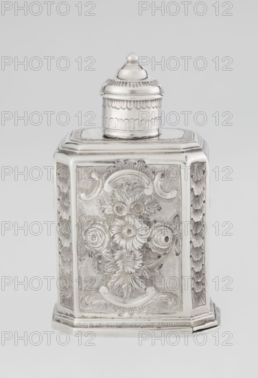 Tea caddy by Nash, Bowles fl. 1720–ca.1725 goldsmith; rococo style; made for loose-leaf tea. Cuboid tea caddy with a circular domed lid and a bowl on the top; chamfered side edges; movable slide-in bottom. Surface decorated with repoussé ornament of floral and rocaille motifs on a grained background; front features an oval rocaille cartouche topped with an eagle, with engraved inscription inside: KENNETH Mc LEOD, / to his much loved Sister / ANNE ZABA, / Octr 23 rd 1848; back wall with a bouquet of flowers; side walls with blooming, leafy roses. Engraved A on the bottom; 1723/1724 tins; ca. mid-19th century decoration; made in London, England. Vessel; height 12 cm, width 7.7 cm, depth 5.7 cm, weight ca. 230 g., A silver container with a domed lid sits centered in the image, showing a rectangular body with beveled edges and an ornate raised floral design on its front panel; the surface displays detailed engraved patterns and textured backgrounds, with decorative scalloped and leaf-like ...