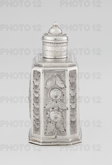 Tea caddy by Nash, Bowles fl. 1720–ca.1725, goldsmith; rococo style. Cuboid tea caddy with a circular domed lid and a bowl on the top; chamfered side edges; movable slide-in bottom. Surface decorated with repoussé ornament with floral and rocaille motifs on a grained background; front features an oval rocaille cartouche topped with an eagle, with engraved inscription inside: KENNETH Mc LEOD, / to his much loved Sister / ANNE ZABA, / Octr 23 rd 1848; back wall with a bouquet of flowers; side walls with blooming, leafy roses. Engraved A on the bottom. Date: 1723/1724 tins; mid-19th century decoration. Place of origin: London, England. Function: vessel for loose-leaf tea tea accessory. Materials: metal tins. Dimensions: height 12 cm, width 7.7 cm, depth 5.7 cm; weight ca. 230 g., A single ornate metallic container with a hexagonal base and a domed removable lid sits against a plain background; the surface shows intricate raised floral and leaf motifs on each vertical panel and scalloped d...
