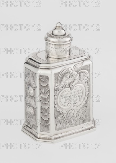 Tea caddy by Nash, Bowles fl. 1720–ca.1725, goldsmith; rococo style. Cuboid tea caddy with a circular domed lid and a bowl on top; chamfered side edges; movable slide-in bottom. Surface decorated with repoussé ornament of floral and rocaille motifs on a grained background; front with an oval rocaille cartouche topped with an eagle, containing engraved inscription KENNETH Mc LEOD, / to his much loved Sister / ANNE ZABA, / Oct 23rd 1848; rear with a bouquet of flowers; sides with blooming, leafy roses. Engraved S on the bottom; 1723/1724 tins; mid-19th century decoration. London, England. Vessel. Height 12 cm, width 7.7 cm, depth 5.7 cm, weight ca. 230 g., A silver metal container with an octagonal base and a domed screw-on lid sits against a plain light gray background; the container is decorated with embossed floral and feather motifs and framed panels, showing a raised bird design on one panel and ornate scrollwork on others, with textured stippling and repeating scalloped patterns on...