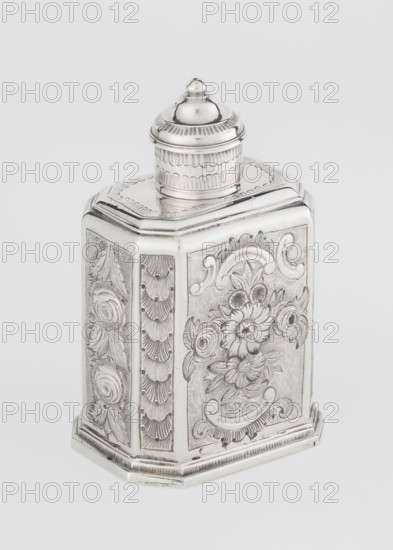 Tea caddy by Nash, Bowles fl. 1720–ca.1725 goldsmith; rococo style; made to contain loose-leaf tea. Cuboid tea caddy with circular domed lid and a bowl on top; chamfered side edges; movable slide-in bottom. Surface decorated with repoussé floral and rocaille motifs on a grained background; front with an oval rocaille cartouche topped by an eagle, with engraved inscription inside: KENNETH Mc LEOD, / to his much loved Sister / ANNE ZABA, / Oct 23 rd 1848; back with a bouquet of flowers; sides with blooming, leafy roses. Engraved S on the bottom; 1723/1724 tins; ca. mid-19th century decoration; London, England, Great Britain. Vessel; height 12 cm, width 7.7 cm, depth 5.7 cm; weight ca. 230 g., A decorative metallic container with a domed lid sits against a plain light gray background; the container has an ornate hexagonal shape with embossed floral and scrollwork patterns on its panels, including raised flowers and leaves, and scalloped and fan-like textured bands on the sides, all in a s...