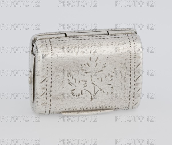 Fragrance container vinaigrette in the form of a bag with an envelope closure and protruding tongue; decorated on the front with dot-engraved flowers and leaves. Hinged lid opening to an interior openwork insert decorated with plant scrolls. Scrap—purchase, Maker: Thomas Shaw fl. 1822–ca. 1840; 1782–1845, goldsmith. Date: 1834/1835. Materials/technique: engraving, openwork. Function: toiletry accessory. Dimensions: height 2.1 cm × width 1.5 cm × depth 1 cm; weight 10 g. Place: Birmingham, England, Great Britain., A small rectangular metal box with a hinged lid sits on a light background; the surface of the box is silver-colored with a slightly tarnished patina and shows etched decorative markings including a floral motif on the top and patterned borders around the edges; the metal has visible scratches and small dents, and the hinge area and corners show slight irregularities in shape.