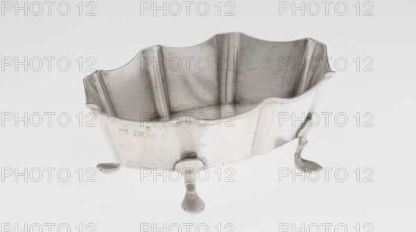 Vase by Mappin & Webb Ltd goldsmith, silversmith, dealer; fl. 1859- maker, ribbed oblong silver vase, vertically ribbed with a wavy-cut edge, supported by four curved legs, 1901–1902, London, England, Great Britain; vessel; height 6 cm, width 15.5 cm, depth 10.5 cm; weight 173 g., A metal container with a scalloped rim and fluted vertical panels sits on three decorative feet; the surface is silver-gray with areas of darker gray patina and subtle scratches, and the interior shows similar silver-gray tones with faint wear marks.