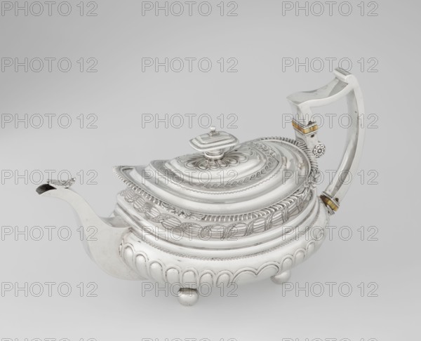 Teapot, George McHattie fl. 1799–ca. 1825, goldsmith. Rectangular teapot with rounded edges, supported by four ball feet. Decorated with hoardings ornament at the bottom, above which are two smooth half-cylinders; at the narrowing is an engraved band of braid. Upper edge has a collar decorated with hoardings and flowers. Hinged, rectangular, profiled lid edged with tendril. Spout-shaped spout set high on the axis; broken ear with bone insulators. English Regency style. Tea vessel. Inscribed/dated 1819–1820. Edinburgh, Scotland, Great Britain. Materials/details: vessel; height 16 cm, width 28.5 cm, depth 13.5 cm, weight 735 g., A silver teapot with ornate raised and engraved decoration sits on a light gray background; the body is rounded with scalloped lower panels and rests on a few small spherical feet, the lid is domed with layered concentric bands and a floral rosette around a central finial, and the spout curves outward ending in a slightly flared tip with decorative detail. The ha...